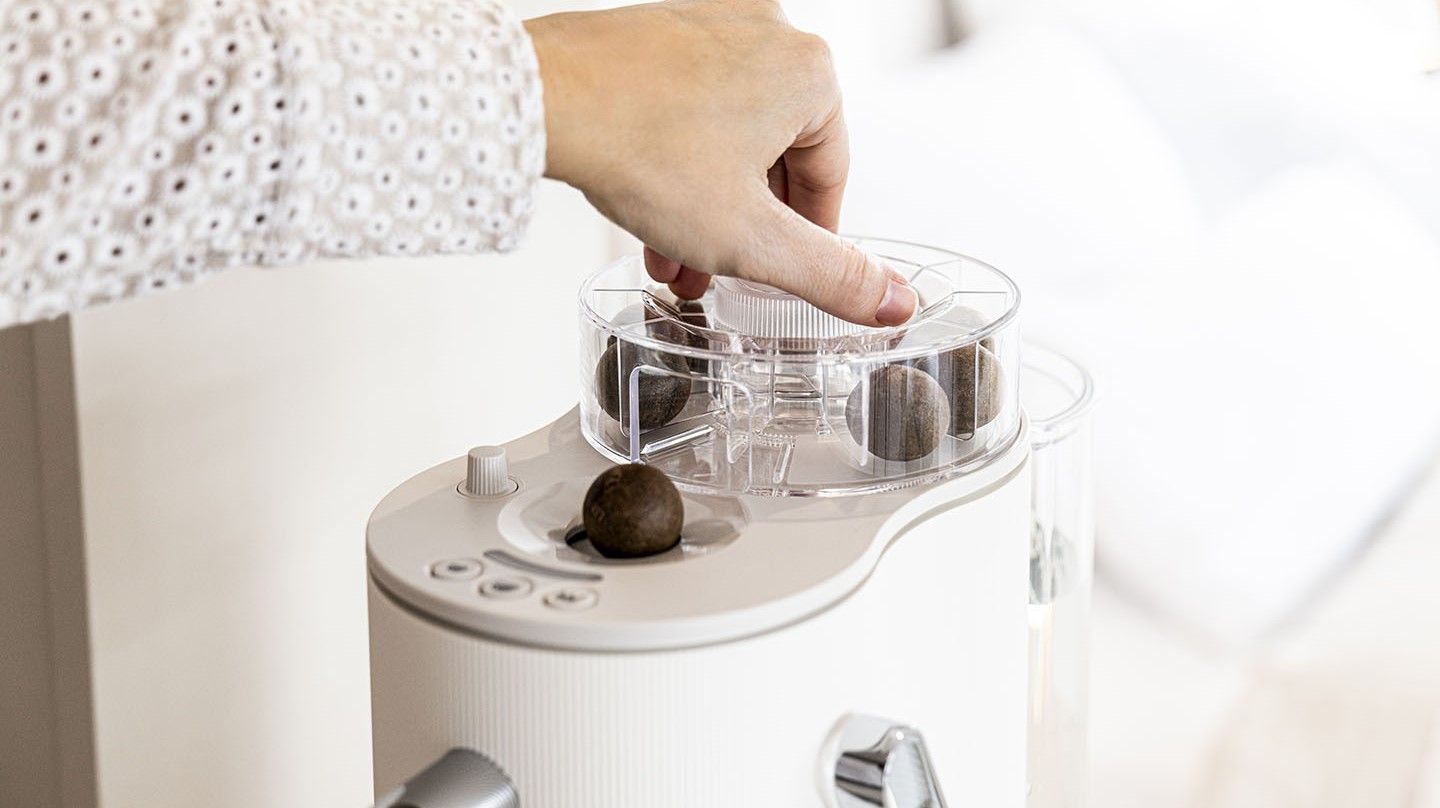 Eine Hand bedient den Coffee Ball Dispenser auf einer Kaffeemaschine