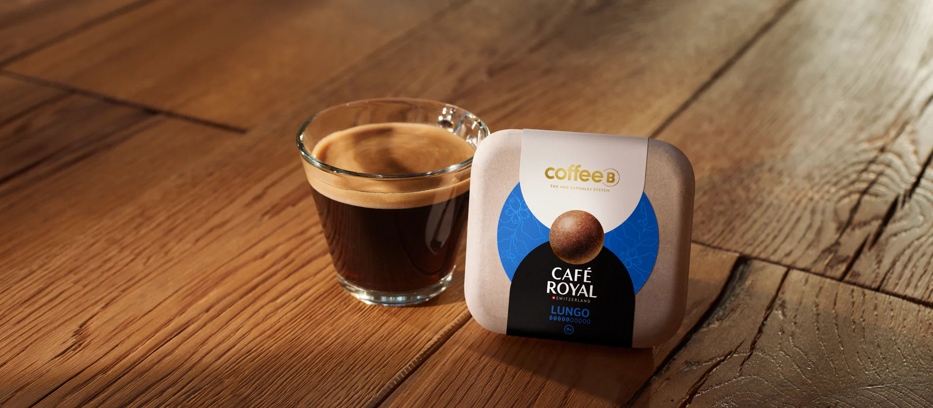 Eine Glastasse mit Kaffee und eine Coffee Ball Verpackung stehen auf einem Tisch